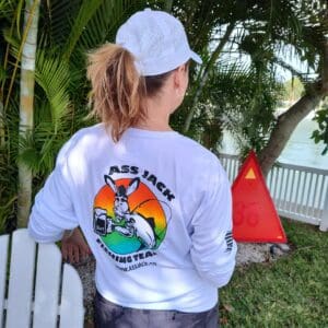 A woman wearing a hat and shirt standing in front of trees.