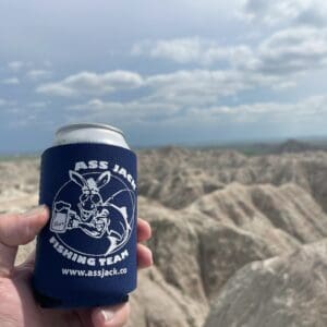 A person holding a can of beer in front of some mountains
