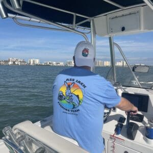 A man in blue shirt on boat with water and buildings.
