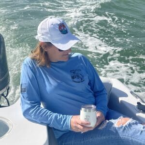 A woman sitting on the back of a boat holding a can.