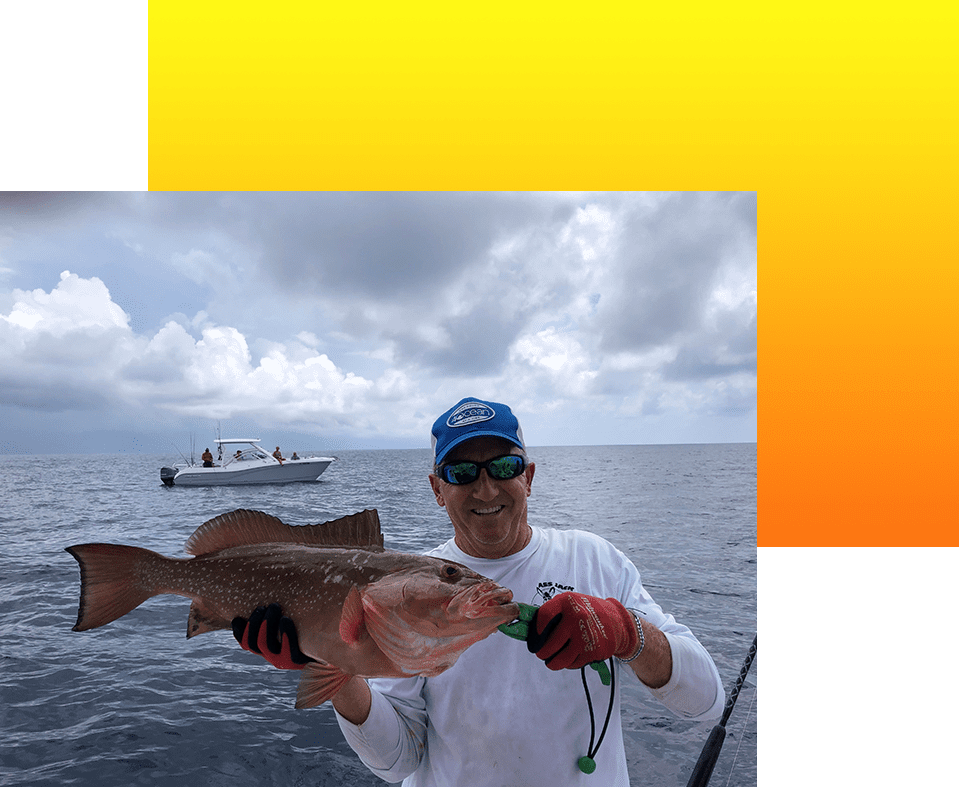 A man holding a fish while standing on top of a boat.